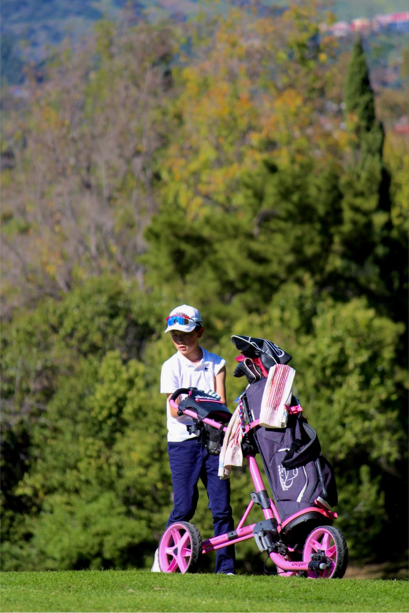 A young Jucchou Golf junior on the course with their golf bag and push cart